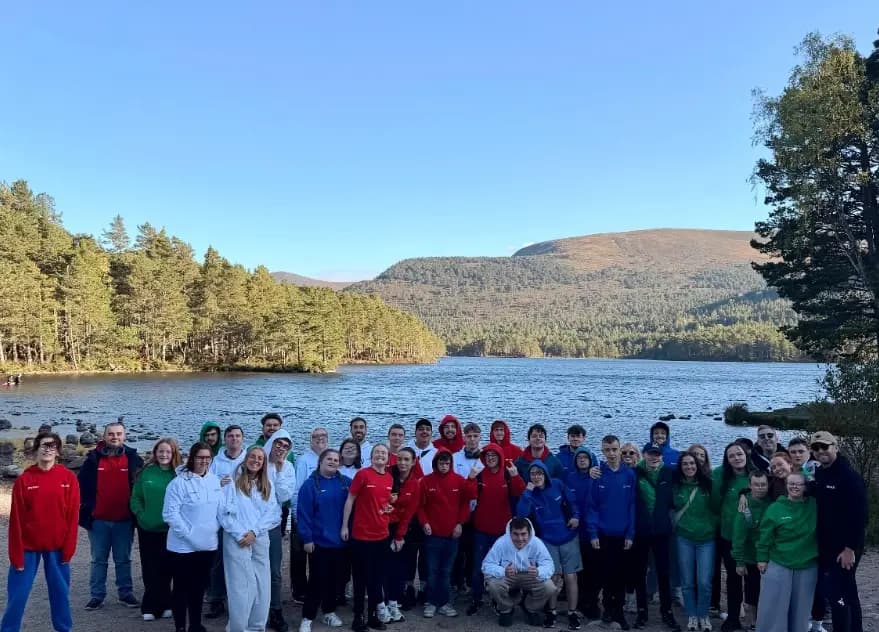 AWARE Scotland young people and volunteers in a group photo on the shore of Loch an Eilein